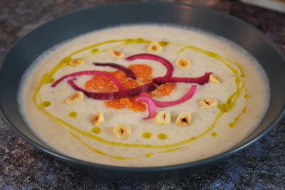 حساء الخرشوف في القدس مع البصل الأحمر المخلل، وبطارخ السمك الأبيض، والبندق المحمص
