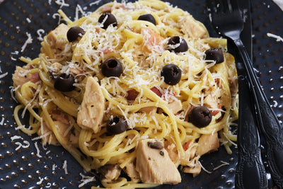 Hühnchen-, Speck- und Pilznudeln mit cremiger Weißwein-Senfsauce, garniert mit Oliven und Parmesan