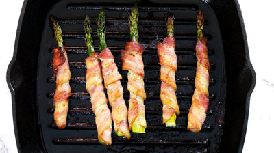 Espargos embrulhados em bacon em uma grelha de ferro fundido