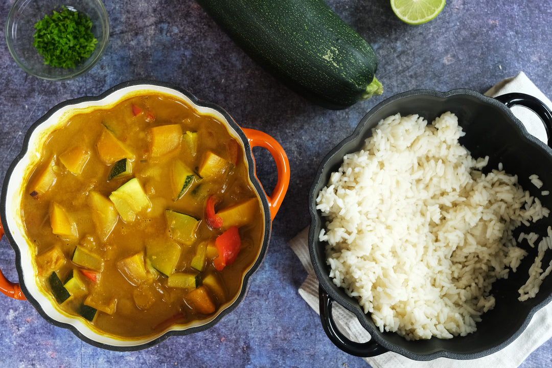 Enameled Cast Iron Pumpkin Pot in orange with curry beside a black pumpkin pot